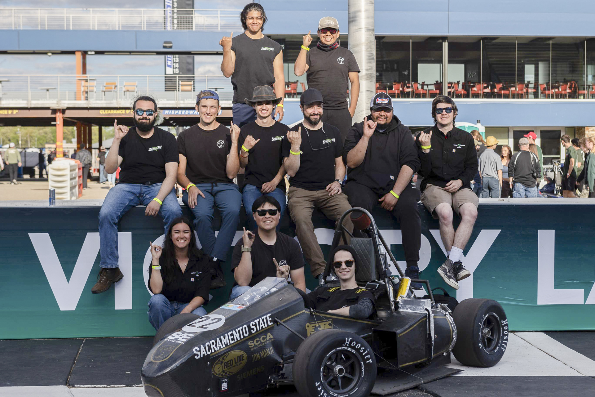 Members of the Sacramento State Hornet Racing team pose for photos with their race cars.